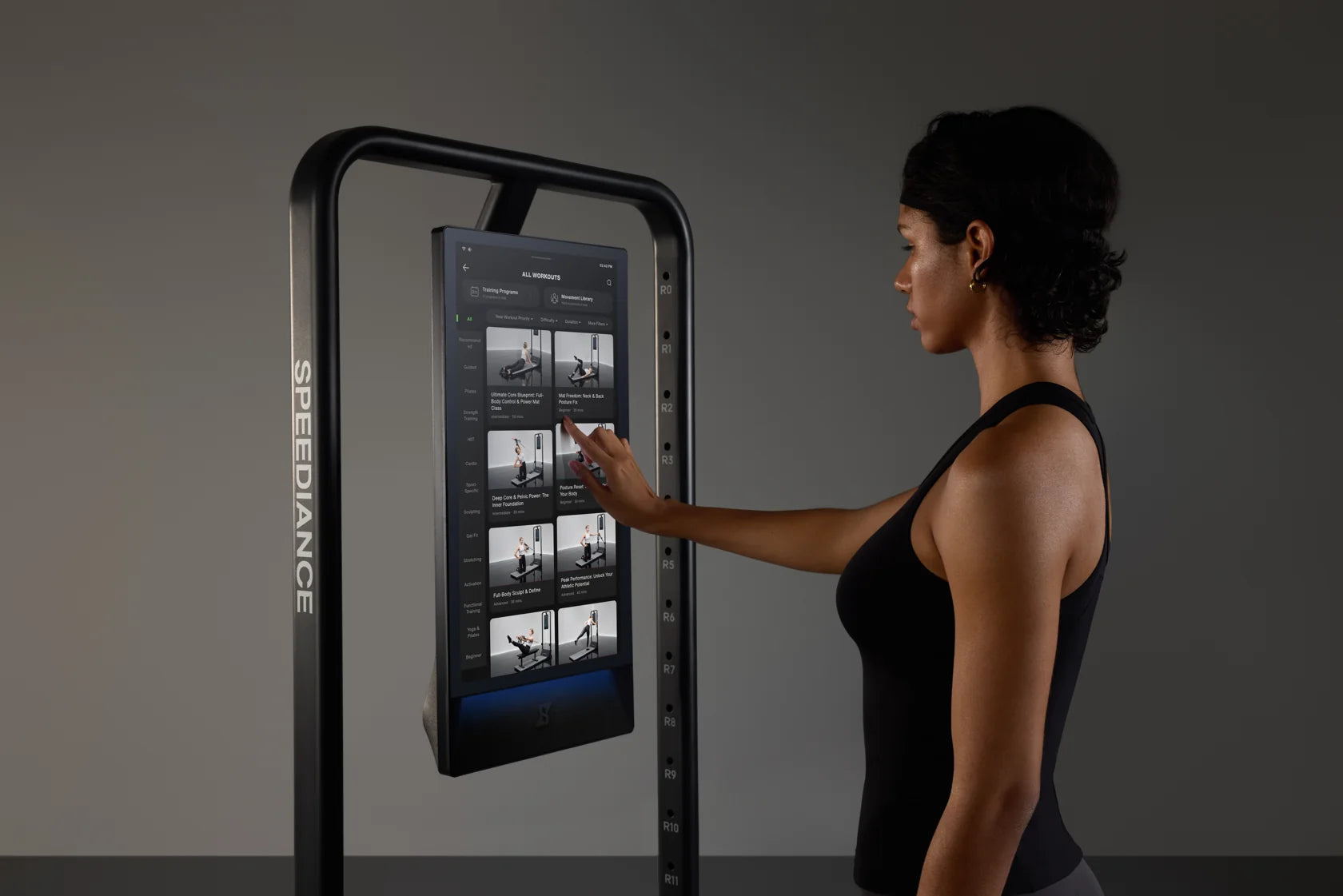 A woman choosing a workout on Gym Monster 3's touchscreen